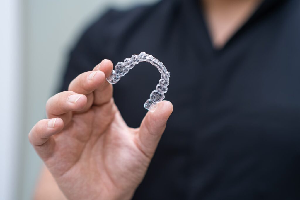 Clear Invisalign aligner held by hand