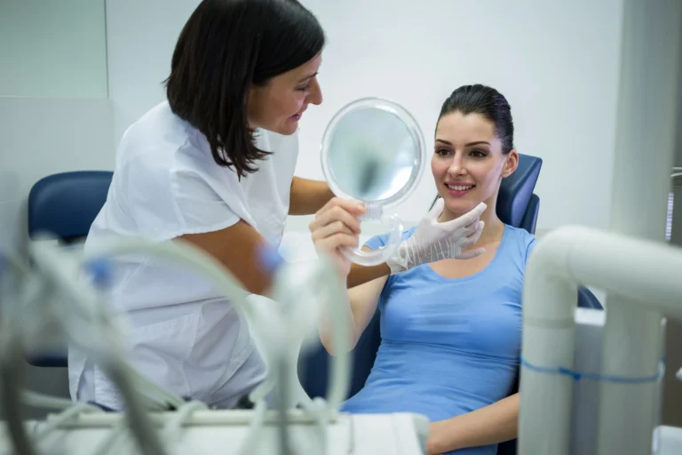 Smiling patient looking at her teeth in a mirror after a dental checkup and cleaning.