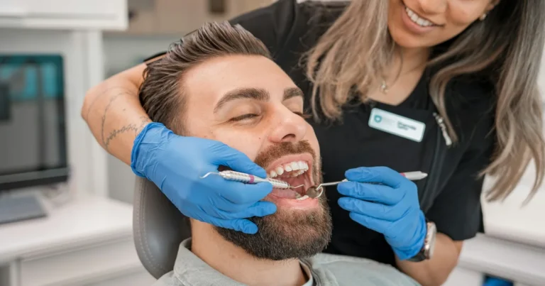 Dental professional examining a patient's teeth with a mouth mirror and explorer in a dental chair